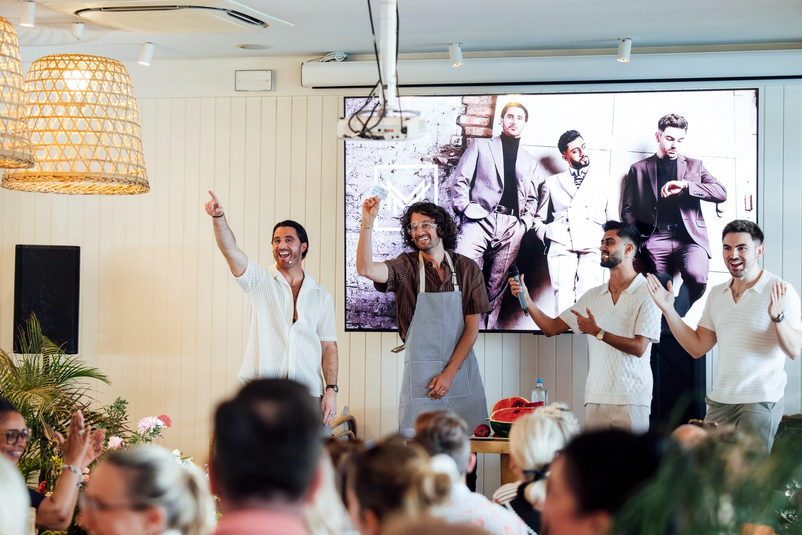Maverick Magicians 7 (1) Photo of Maverick Magicians entertainment who are three male magicians reacting to a crowd at an event infront of a projector screen